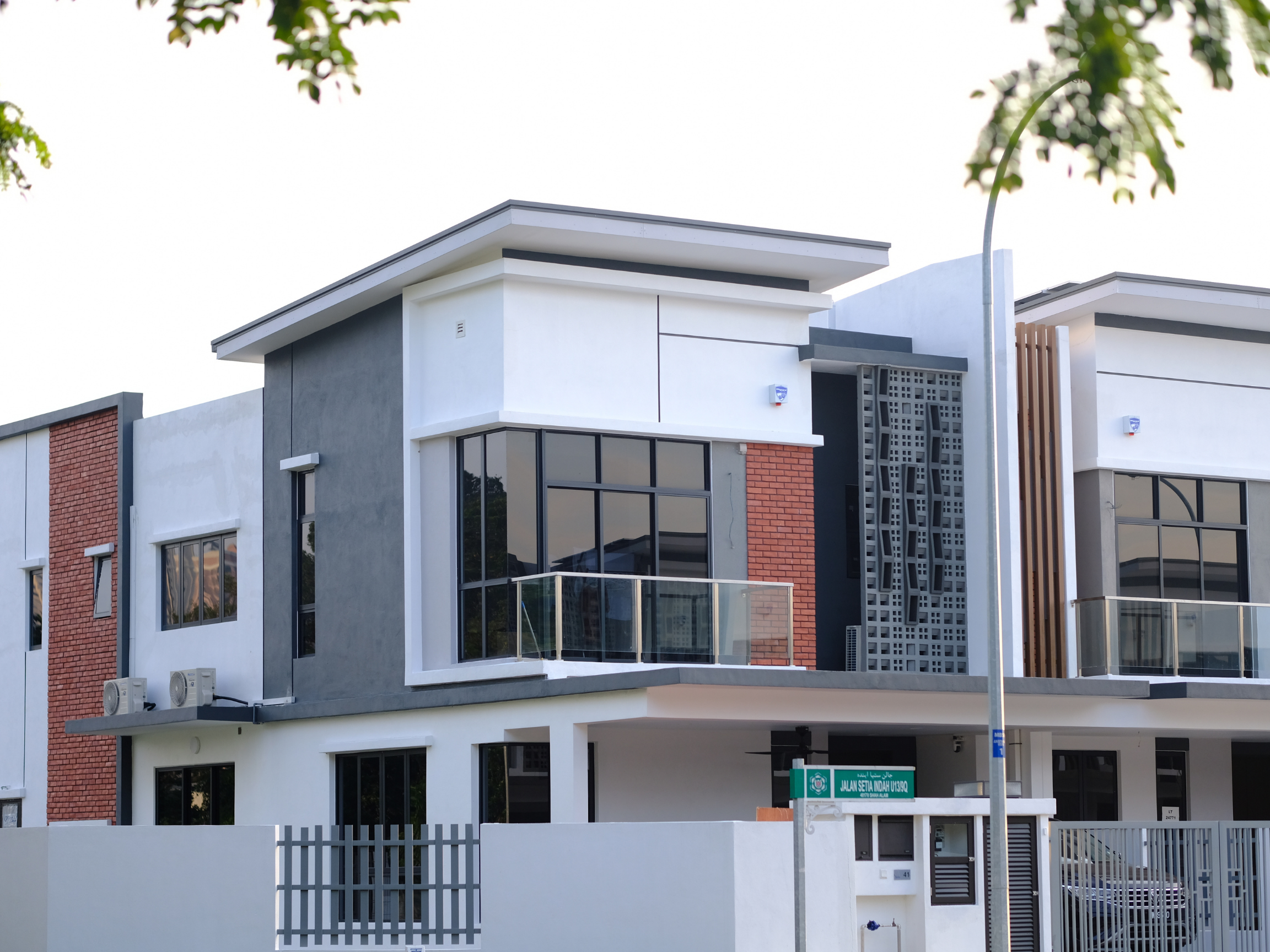Modern townhouse-style residential building with brick accents and glass balcony railing.